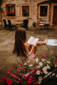 a girl sitting in a chair reading a book at BioRezydencja in Świeradów-Zdrój