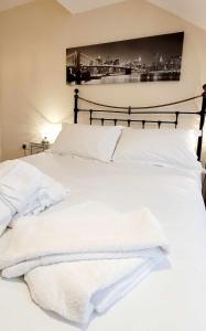 a bed with white sheets and towels on it at Apartment 4 - striking, 2 bedroom luxury apartment - close to town, mainline rail & theatre in Darlington