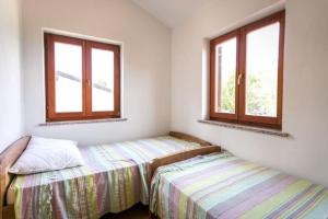 two beds in a room with two windows at Apartment Beach Stara Porozina in Porozina