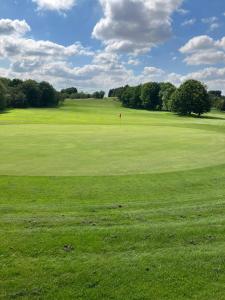 un campo de golf verde con bandera roja a lo lejos en Premium Inn Apartments en Methley