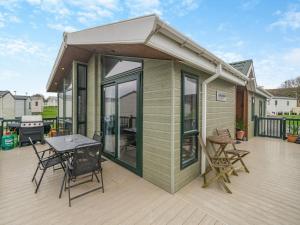 una casita verde pequeña con una mesa y sillas en una terraza en Sea View Lodge, en Horden