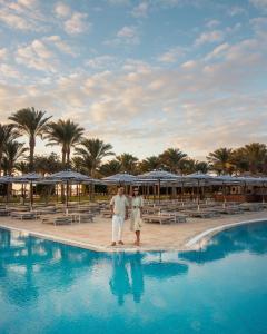 a man and woman standing next to a swimming pool at Siva Grand Beach in Hurghada