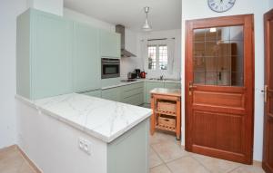 a kitchen with green cabinets and a clock on the wall at Beautiful Home In Aigues-mortes With 3 Bedrooms And Wifi in Le Grau-du-Roi