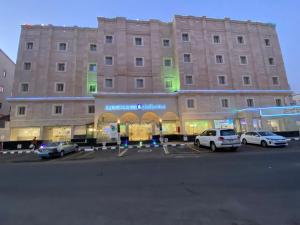 a large building with cars parked in a parking lot at Al Andlus Palace Hotel 2 in Al Madinah