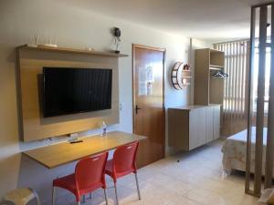 a living room with a table and chairs and a television at Excelente Loft 1 novíssimo no Centro de Saquarema in Saquarema