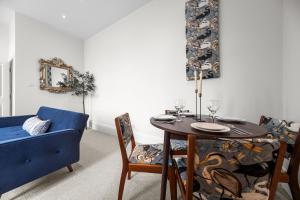 a dining room with a table and a blue couch at Pelican Suite 1 Bed Apartment in Harrogate