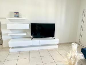 sala de estar blanca con TV de pantalla plana en Luxury Simpson bay condo en Koolbaai