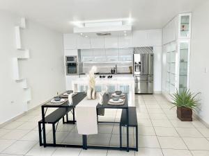a white kitchen with a dining table and a kitchen with stainless steel appliances at Luxury Simpson bay condo in Koolbaai