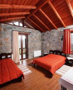 a bedroom with two beds and a stone wall at Arodamos Guesthouse in Krousón