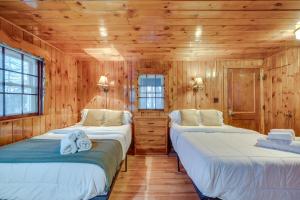 two beds in a room with wooden walls at Cozy Laconia Studio with Pool Access - 2 Mi to Lake! in Laconia