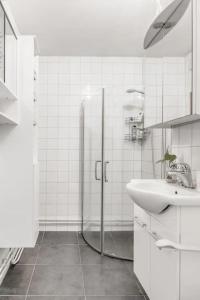 La salle de bains blanche est pourvue d'un lavabo et d'une douche. dans l'établissement Karlstad Unic House kronoparken, à Karlstad