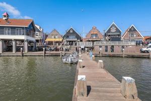 a dock with a boat in the water next to buildings at Cosy tiny house in the centre city of Volendam in Volendam