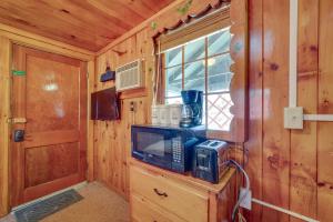 a living room with a tv and a window in a cabin at Rustic Laconia Studio Cabin about 2 Mi to Weirs Beach! in Laconia