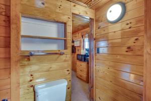 a bathroom with a toilet and wooden walls at Rustic Laconia Studio Cabin about 2 Mi to Weirs Beach! in Laconia