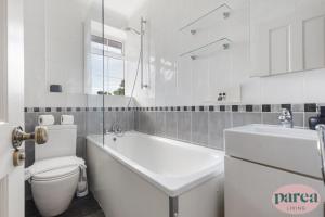 a bathroom with a tub and a toilet and a sink at Parea Living - Stylish Islington 1-Bed Flat, 6min Walk to Tube in London