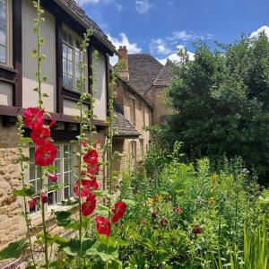 a garden with red flowers in front of a house at Spacious Cottage in the Centre of Burford, Cotswolds in Burford