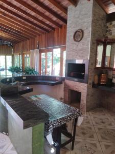 uma sala de estar com uma lareira de pedra e uma mesa em Sítio refúgio do lago em Piracicaba