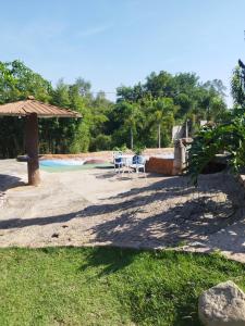 un patio con sillas y una sombrilla junto a la piscina en Sítio refúgio do lago en Piracicaba