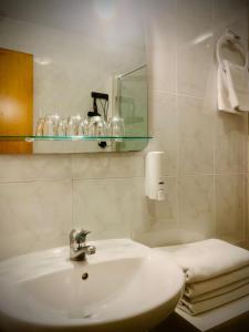 Baño blanco con lavabo y espejo en Hostal As Margaritas, en Santiago de Compostela