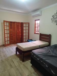 1 dormitorio con 2 camas y ventana en Sítio refúgio do lago en Piracicaba