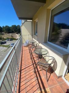 four tables and chairs on a balcony with a large window at Apartament „Na wydmie” in Ustka