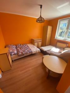 a bedroom with orange walls and a bed and a table at Apartament „Na wydmie” in Ustka