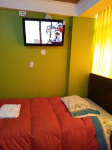 a bedroom with a bed with a tv on the wall at HOSTAL JOYA ANDINA in Puno