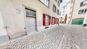 a cobblestone street with a white door on a building at 2 Zimmerwohnung - Zentral - 65“ TV - Arbeitsplatz in Chur