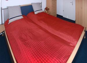 łóżko z czerwoną kołdrą na górze w obiekcie Seeblick Wohnung 121 w Koserowie