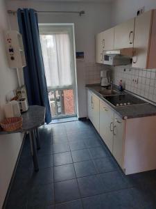 a small kitchen with white cabinets and a large window at Seeblick Wohnung 116 in Ostseebad Koserow