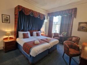 een slaapkamer met een kingsize bed en een baldakijn bij Lovat Arms Hotel in Beauly