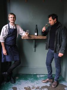 Nest Farmhouse في Docking: اثنين من الرجال واقفين بجوار طاولة مع كؤوس النبيذ