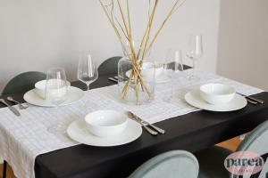 a black table with white plates and glasses on it at Parea Living - Notting Hill, Stylish 1-Bedroom Flat, Private Gardens, Remote Working in London