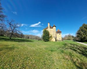 Château à Gourdon dans le Lot في غوردون أون كيرسي: مبنى قديم على حقل عشبي مع السماء الزرقاء