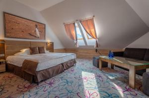 ジキにあるHotel & SPA Czarny Grońのベッドとソファ付きのホテルルーム