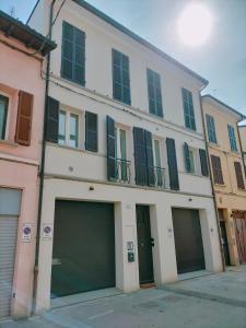 un grand bâtiment blanc avec deux garages devant lui dans l'établissement FaCentro - Pratico flat in centro storico, à Faenza