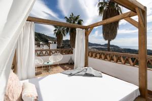 Schlafzimmer mit Blick auf einen Balkon mit Palmen in der Unterkunft Posada Morisca Charming Hotel Boutique in Frigiliana