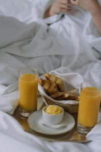 a breakfast tray with a plate of food and two glasses of orange juice at Hotel Samara Kingdom Near Delhi Airport in New Delhi