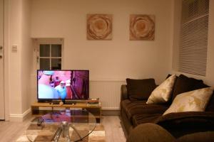 a living room with a couch and a tv at Luxury and serviced 3 bed house - Hampstead Garden in London