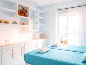 two beds in a white room with a window at Riverside Apartment in Triana in Seville