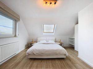 a white bedroom with a bed and a window at Duplex - Appartement 'Tijl Uilenspiegel' - Oostduinkerke in Oostduinkerke