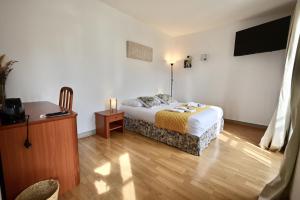 a bedroom with a bed and a table and a television at Hôtel La cuisine des Lulus in Montainville