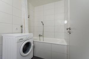 baño blanco con lavadora y lavamanos en T&K Apartments - 3 Room Apartment with Balcony, en Essen