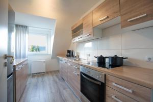 cocina con armarios de madera y fogones en T&K Apartments - 3 Room Apartment with Balcony, en Essen