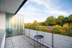 uma varanda com uma cadeira e vista para as árvores em T&K Apartments - 3 Room Apartment with Balcony em Essen