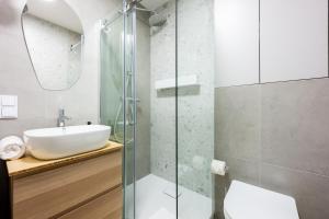 a bathroom with a sink and a glass shower at Native Apartments Kościuszki 39/5 in Kraków +34 photos