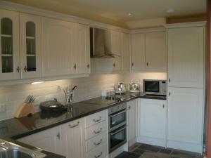 a kitchen with white cabinets and a counter top at Gamekeeper's Cottage in Tobermory