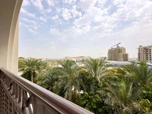 een balkon met uitzicht op palmbomen en gebouwen bij Dar Vacation - Bright and Charming 1 BR Apartment in Dubai