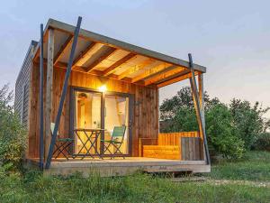 a wooden cabin with a table and chairs in a field at Camping Les Perouses in Saint-Clément-des-Baleines