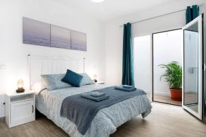 a white bedroom with a bed and a large window at Viviendas El Pescador - Vela in El Golfo